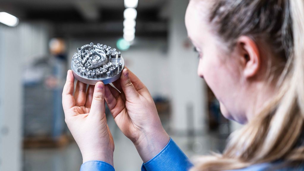 Eine Frau betrachtet eine 3D-gedruckte Dentalplatte